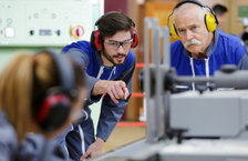 Young male apprenticeship with mentor pointing at machine