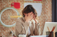 A young woman sitting at her desk with her face in her hands