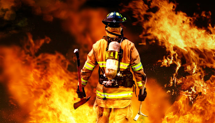 A firefighter walking into a burning building