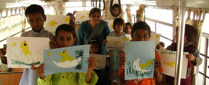 Children inside Karachi’s mobile school bus holding up drawings