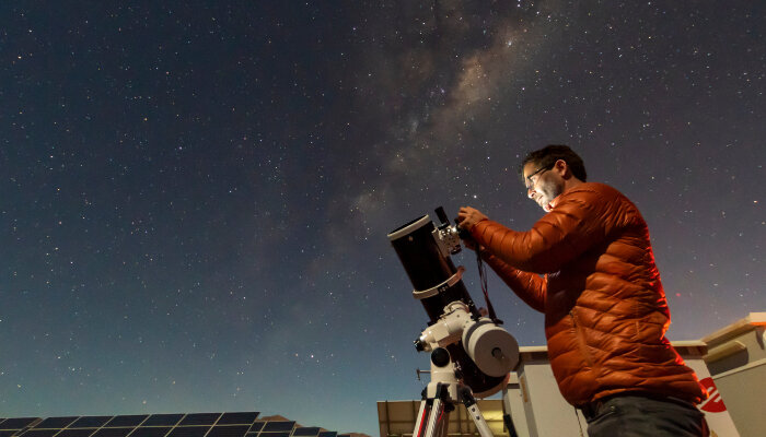 A male astronomer with a telescope during nightfall