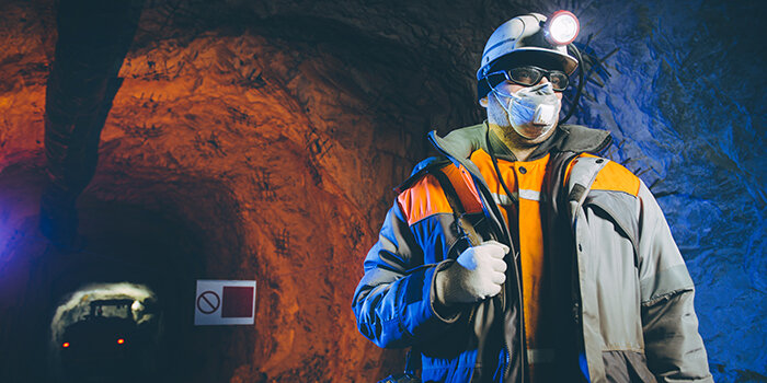 Miner underground with PPE and head torch.