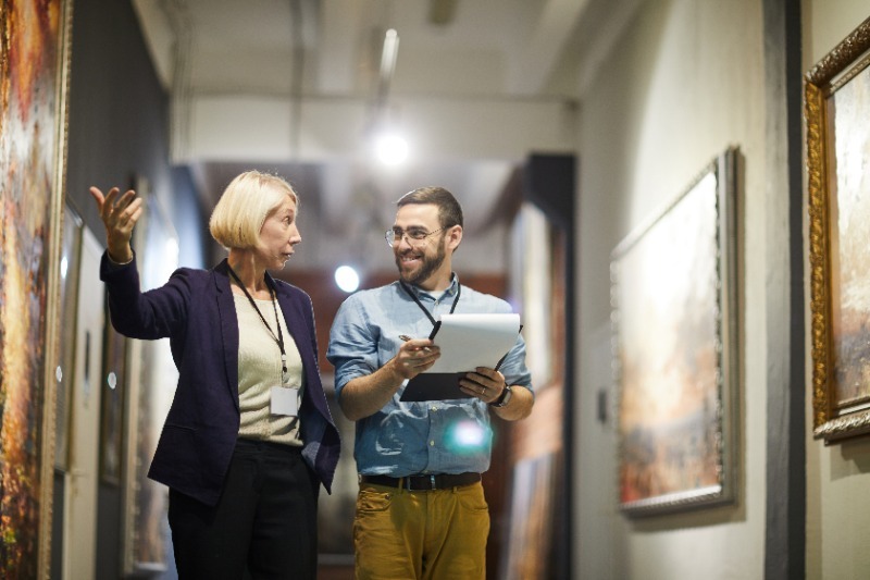 Art curator walking through a hallway decorated with paintings